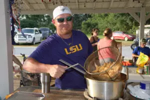 man in blue shirt deep-frying a dish
